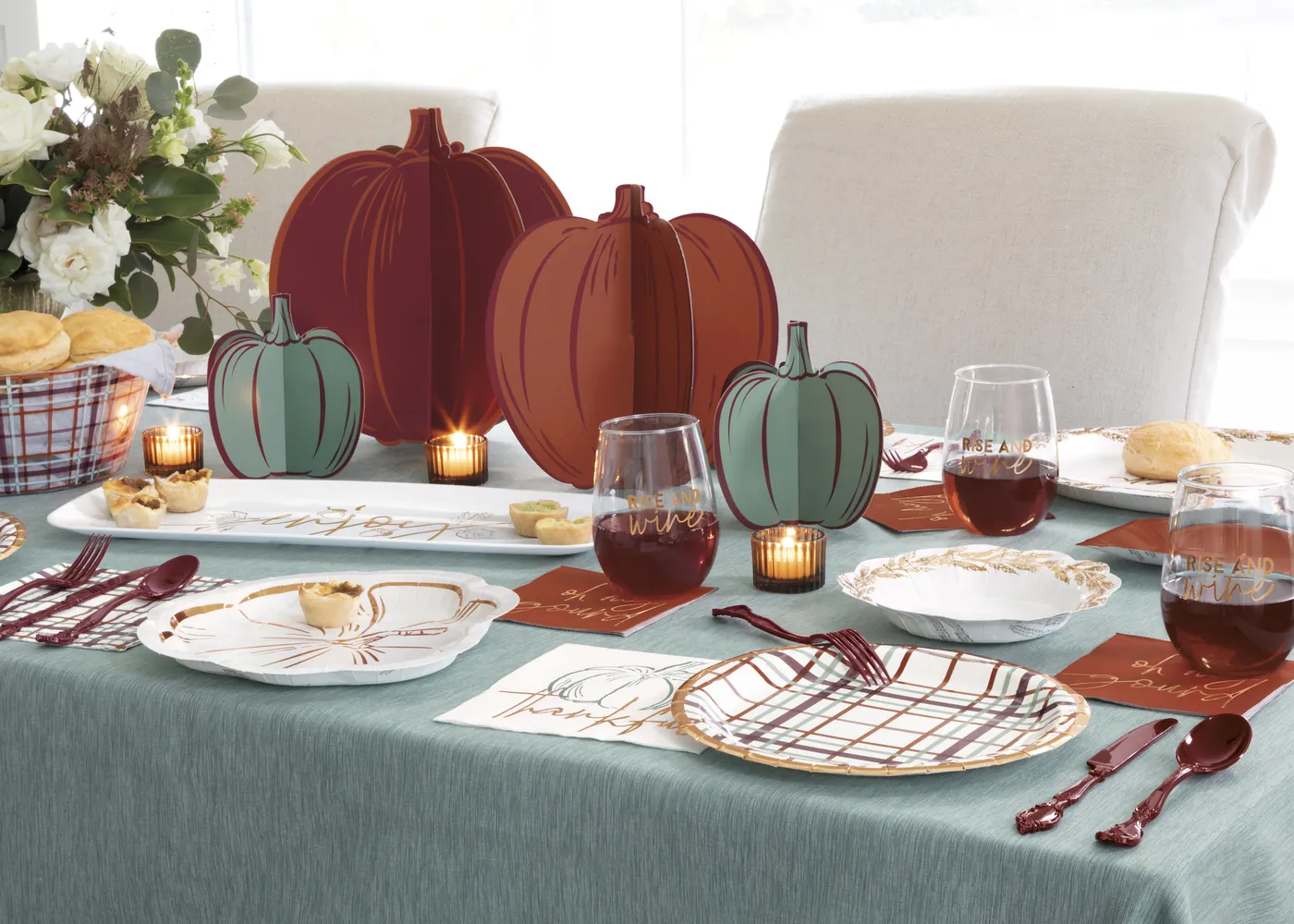 Friendsgiving table set with pumpkin centerpieces, plaid plates and napkins